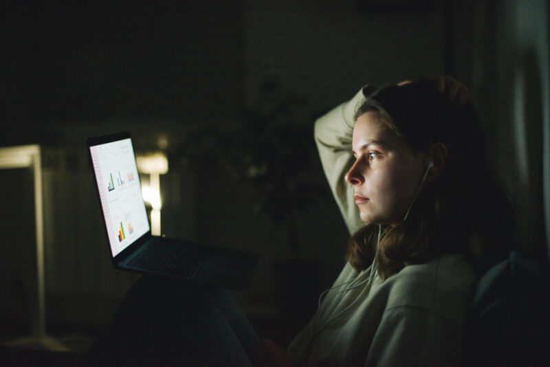 Woman in the dark, illuminated by a screen